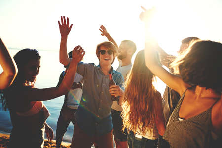 Ecstatic teenage friends dancing on the beachの写真素材