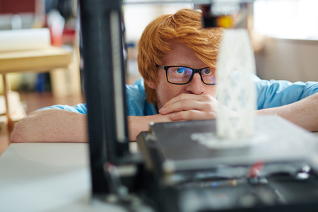 Serious designer looking at new architectural model in 3d printer