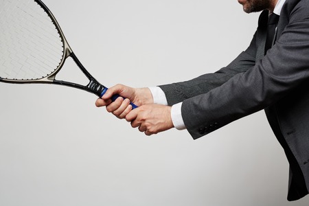 Close-up of businessman in suit holding tennis racketの写真素材