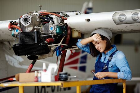 Tired female with wrench standing under air jet partの写真素材