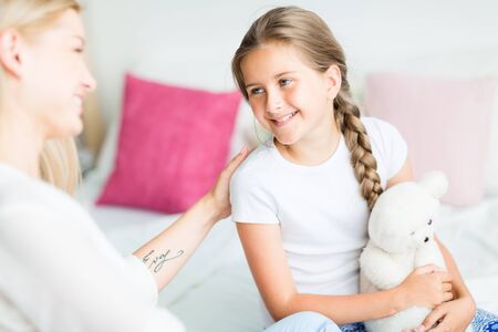 Happy girl with teddybear looking at her motherの写真素材