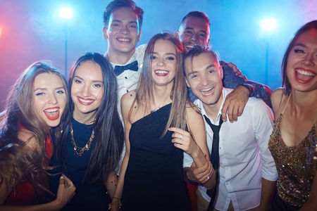 Ecstatic friends looking at camera in night clubの写真素材