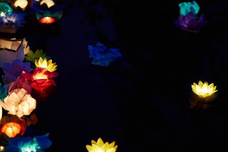 Colorful paper lanterns floating on dark waterの写真素材