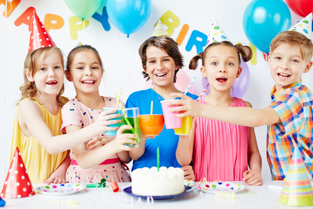 Group of happy kids toasting with drinks at birthday partyの写真素材