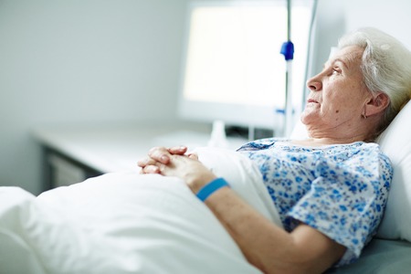Grey-haired sick woman lying in bedの写真素材
