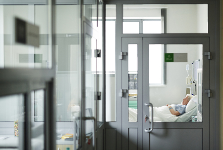 Aged patient sleeping in bed in hospital wardの写真素材
