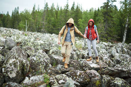 Two adventurous hikers walking down huge stonesの写真素材