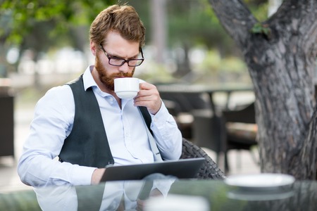 Businessman drinking tea during work in outdoor cafeの写真素材