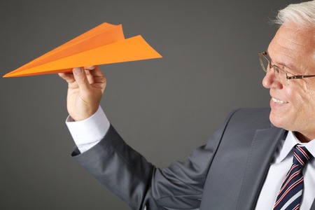 Portrait of senior businessman throwing a paper planeの写真素材
