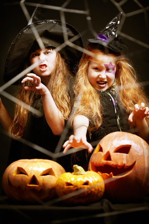 Portrait of little aggressive Halloween girls with pumpkinsの写真素材