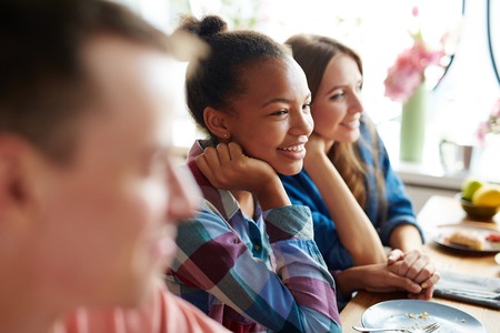Adolescent girl sitting by festive table among her friendsの写真素材