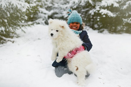 Happy girl holding her pet during play in snowdriftの写真素材
