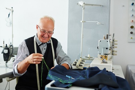 Professional tailor with needle and thread sewing clothesの写真素材