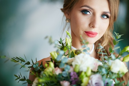 Pretty young bride with flowers looking at cameraの写真素材