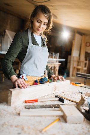 Female carpenter processing wooden plank in workshop