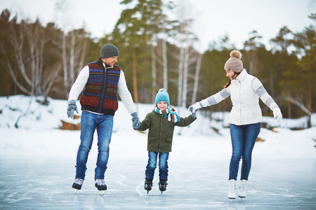 Modern family of father, mother and son skating in natural environmentの写真素材
