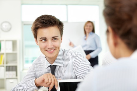 Young man flirting with his neighbor while woman giving a presentationの写真素材