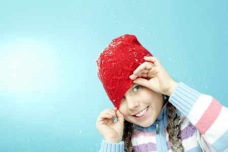 Portrait of little girl in woolen hat winking at cameraの写真素材