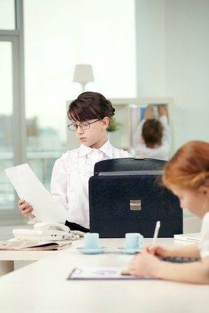 Little girl looking at documents in officeの写真素材