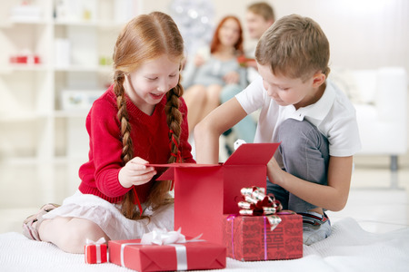 Little boy taking something out of gift box together with his sisterの写真素材