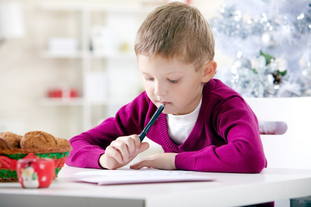 Portrait of little boy writing to Santa Claus on Christmas Eveの写真素材