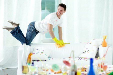 Young man putting his room in order after violent partyの写真素材