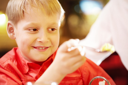 Close-up of a little boy s face holding a spoon and smilingの写真素材