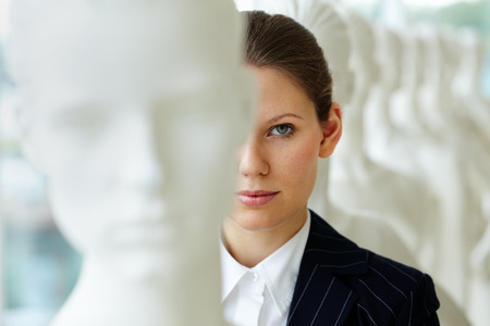 A young woman standing in line with mannequins and looking at cameraの写真素材