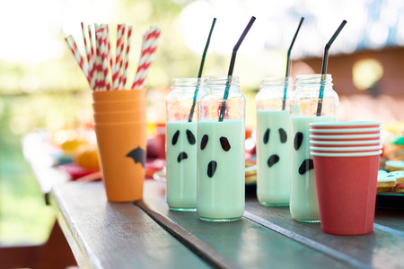 Milk in long jars with straws and plastic glasses on wooden tableの写真素材