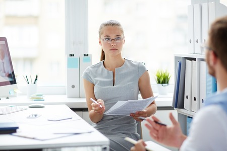 Young specialist listening to her co-worker during discussionの写真素材