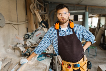 Serious carpenter with tool belt looking at cameraの写真素材