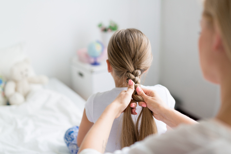 Female plaiting her daughter long hairの写真素材