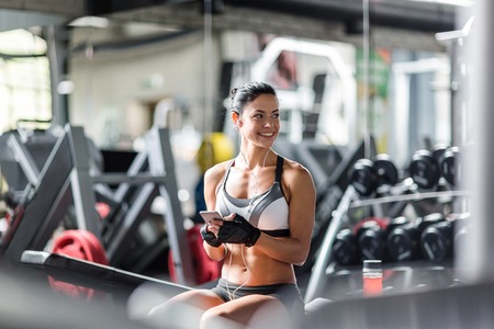 Smiling fit woman listening to music in gymの写真素材