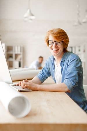 Cheerful businessman sitting by computer in officeの写真素材