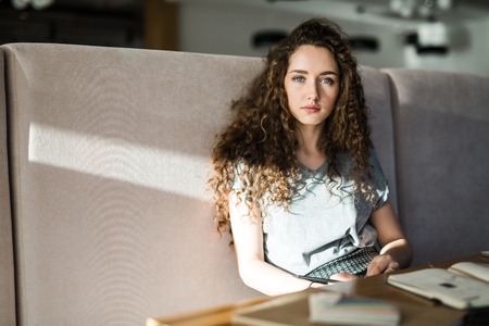 Young pensive female sitting in cafe at leisure