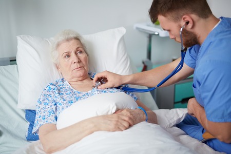 Aged woman having medical treatment in hospital ward