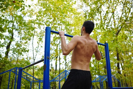 Rear view of topless sportsman pulling up in park