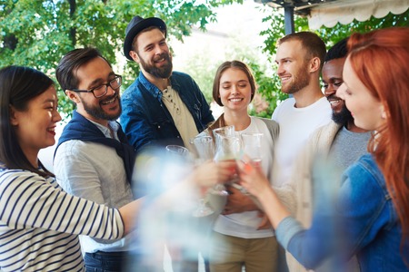 Friends with drinks cheering up during hangoutの写真素材