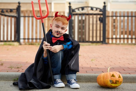 Devil boy with pitchfork looking at camera