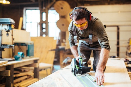 Joiner with fretsaw processing wooden boardの写真素材