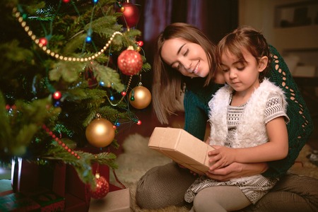 Little girl looking at packed xmas present from her mother