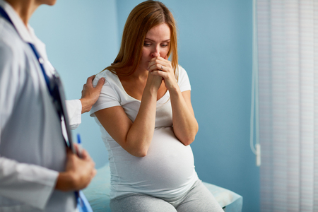Pregnant woman crying with her doctor near byの写真素材
