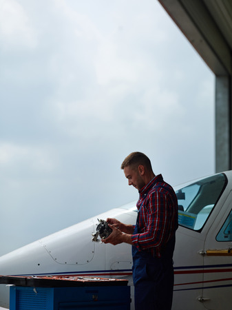Workman in uniform measuring spare part of jet engineの写真素材