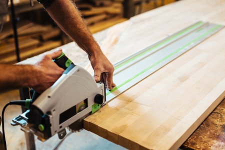 Workman processing wooden board in workroomの写真素材