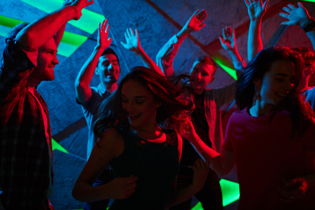 Group of ecstatic teens enjoying dance in night clubの写真素材