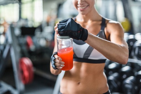 Sporty woman opening bottle with kissel after trainingの写真素材