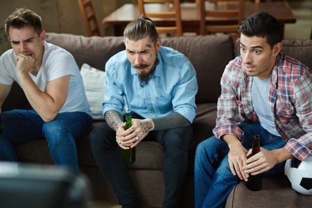 Nervous guys watching tv broadcast of football matchの写真素材