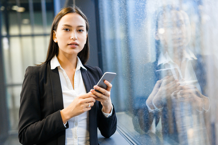 Confident businesswoman with smartphone looking at cameraの写真素材