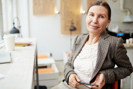 Experienced businesswoman with earphones working in cafe