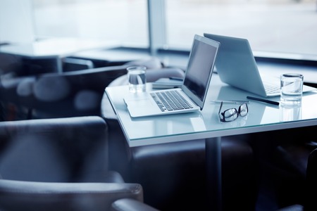 Two laptops, two glasses with water and other objects on deskの写真素材
